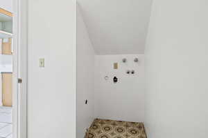 Laundry room featuring vaulted ceiling, hookup for a washing machine, and tile patterned floors