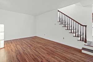 Unfurnished living room featuring dark wood finished floors, stairway, and a textured ceiling