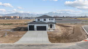 View of front of property featuring stone siding, a mountain view, concrete driveway, and a shingled roof