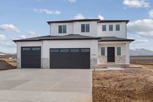 Prairie-style home with stone siding, concrete driveway, a shingled roof, and an attached garage