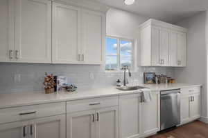 Kitchen with dishwasher, white cabinets, light stone countertops, decorative backsplash, and dark wood finished floors