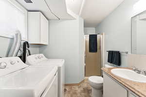 Bathroom with a shower stall, vanity, and washer and dryer