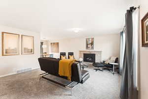 Carpeted living room with a fireplace and baseboards