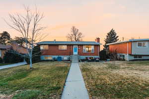 Ranch-style home with a chimney, brick siding, and a front yard