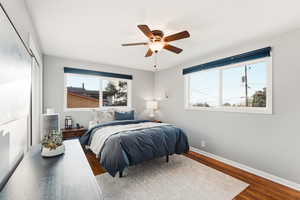 Bedroom with wood finished floors, a ceiling fan, and multiple windows