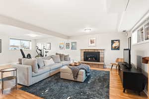 Living area with plenty of natural light, light wood-style flooring, and a stone fireplace
