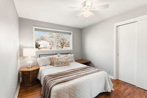 Bedroom with ceiling fan, dark wood-style floors, and a closet