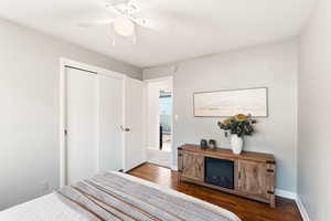 Bedroom with a closet, dark wood-style flooring, and ceiling fan