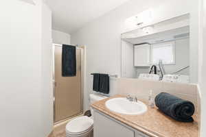 Bathroom featuring backsplash, a shower stall, and vanity