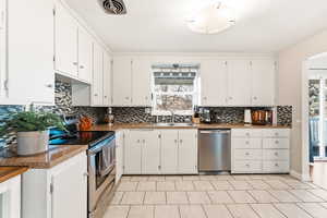Kitchen featuring backsplash, appliances with stainless steel finishes, and white cabinetry