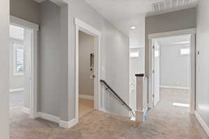 Hall featuring an upstairs landing, light carpet, plenty of natural light, and recessed lighting