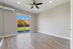 Unfurnished room featuring a ceiling fan, an AC wall unit, recessed lighting, and wood tiled floors