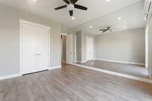Unfurnished living room featuring recessed lighting, ceiling fan, a wall unit AC, and wood finish floors