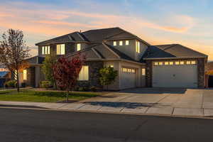 Traditional-style home with a garage, concrete driveway, stucco siding, a front yard, and stone siding