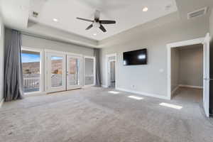 Unfurnished bedroom with a tray ceiling, french doors, access to exterior, a ceiling fan, and recessed lighting