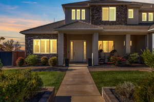 View of front of property featuring stucco siding, stone siding, a tile roof, and covered porch