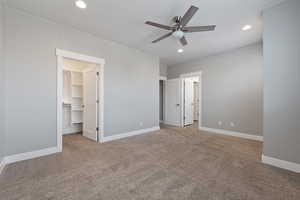 Unfurnished bedroom featuring a walk in closet, light carpet, ceiling fan, and recessed lighting