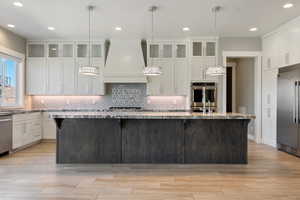 Kitchen featuring glass insert cabinets, backsplash, white cabinets, and recessed lighting