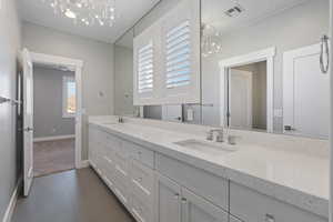 Full bathroom featuring a chandelier, double vanity, and dark tile patterned flooring