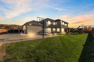 Rear view of property featuring a fenced backyard, a playground, stucco siding, and a patio area