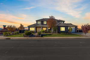 Traditional-style home with a lawn, driveway, stone siding, and a tiled roof