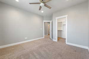 Unfurnished bedroom with a walk in closet, light colored carpet, ceiling fan, and recessed lighting