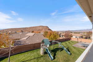 Fenced backyard with a playground, a mountain view, a residential view, and a balcony