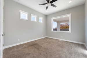 Carpeted spare room featuring plenty of natural light, a ceiling fan, and recessed lighting