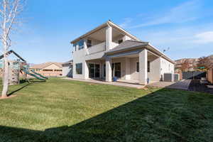 Back of house with a patio, stucco siding, a balcony, and a playground