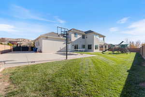 Rear view of house with a fenced backyard, a patio, a playground, basketball hoop, and stucco siding