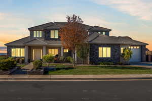 Traditional-style house with an attached garage, stone siding, and a lawn