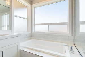 Bathroom featuring vanity, a bath, and healthy amount of natural light