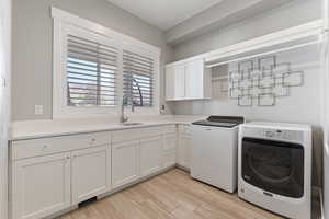Laundry room with light wood-type flooring, washer and dryer, and cabinet space