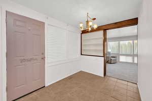 Unfurnished dining area with a chandelier, light colored carpet, and light tile patterned floors