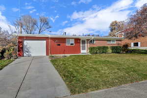 Ranch-style house featuring a front lawn, concrete driveway, an attached garage, and brick siding