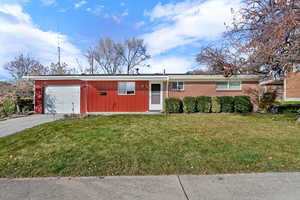 Ranch-style home featuring concrete driveway, a front lawn, and a garage
