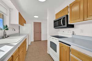 Kitchen with white appliances, light countertops, and light tile patterned floors