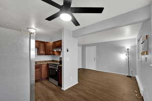 Kitchen featuring new appliances with stainless steel finishes, a baseboard heating unit, LVP wood-style floors, brand new ceiling fan, and wood cabinetry