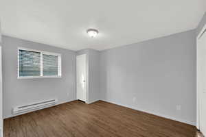 Bedroom with a baseboard radiator, fresh coat of paint and brand new LVP wood-style floors