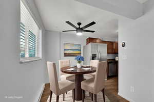 Virtually Staged Dining area featuring a baseboard heating unit, new LVP wood-style floors, and new ceiling fan