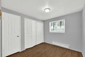 Second bedroom with newly painted with baseboard heating, new LVP dark wood-type flooring, and a closet