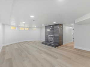 Unfurnished living room with a large fireplace, recessed lighting, and light wood-style flooring