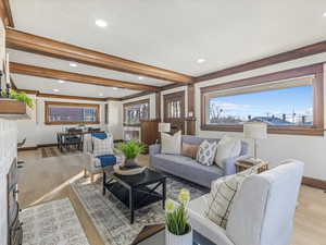 Living area with a fireplace, light wood-type flooring, beam ceiling, and recessed lighting