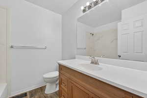 Full bath with vanity, dark wood-style floors, and bathtub / shower combination