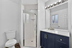 Bathroom with vanity, a shower stall, and dark wood-type flooring