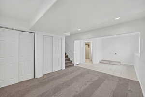 Finished below grade area with light colored carpet, stairs, light tile patterned flooring, and recessed lighting