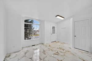 Unfurnished room with light marble finish floors and lofted ceiling