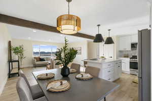 Dining room with beam ceiling, light wood-style flooring, and recessed lighting