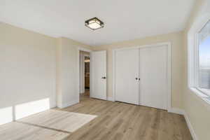 Unfurnished bedroom featuring light wood-style flooring and a closet