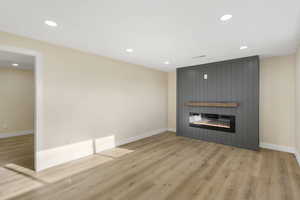 Unfurnished living room featuring light wood finished floors, recessed lighting, and a fireplace